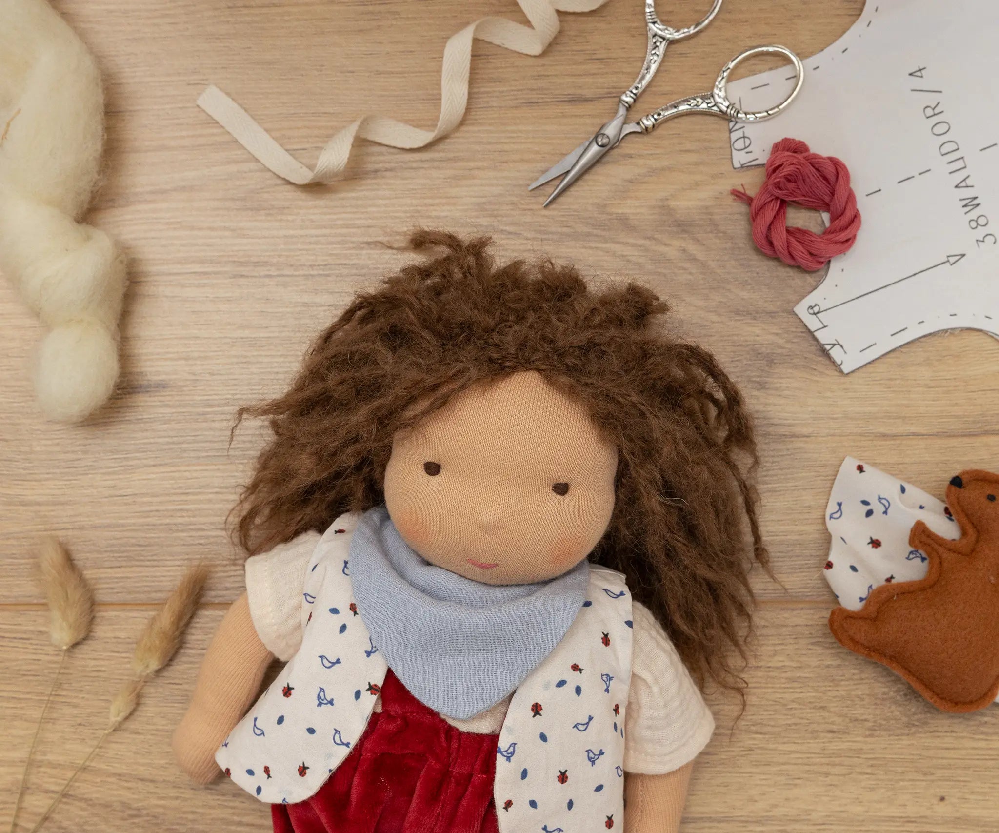 Käthe Kruse Waldorf doll Toni with it's hat taken off and materials from making process around it.