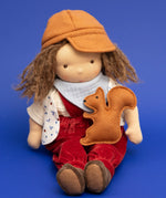 Käthe Kruse Waldorf doll Toni in a sitting position with a small felt squirrel on it's lap. 
