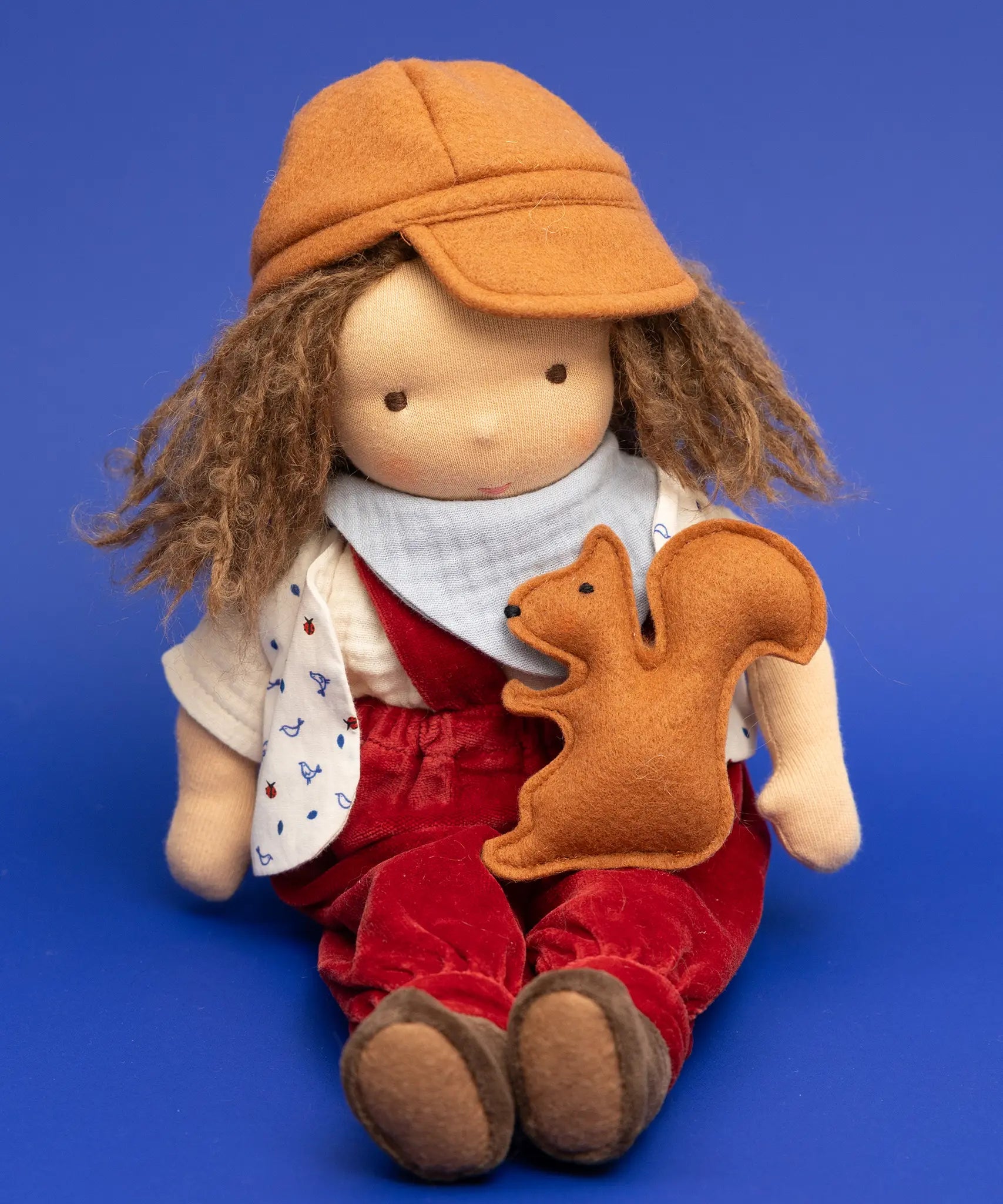 Käthe Kruse Waldorf doll Toni in a sitting position with a small felt squirrel on it's lap. 