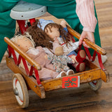 Käthe Kruse Waldorf doll Hannah and other dolls placed in the trailer of a bike ridden by a child. 