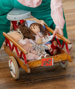 Käthe Kruse Waldorf doll Hannah and other dolls placed in the trailer of a bike ridden by a child. 