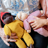 Adult holding a Safron waldorf doll from kathe kruse and a child holding a pink waldorf doll