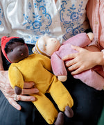 Adult holding a Safron waldorf doll from kathe kruse and a child holding a pink waldorf doll
