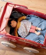 Käthe Kruse Waldorf Doll Kiki laying in a red doll's pram.