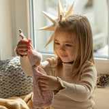 Käthe Kruse rose pink small Waldorf Imp doll comforter toy made with cotton muslin held in a child's hand. 