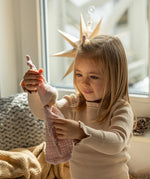 Käthe Kruse rose pink small Waldorf Imp doll comforter toy made with cotton muslin held in a child's hand. 