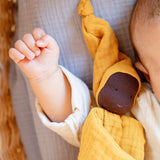 Käthe Kruse ocre yellow small Waldorf Imp doll baby comforter. Soft toy is placed on a baby's arm.