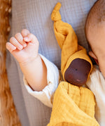 Käthe Kruse ocre yellow small Waldorf Imp doll baby comforter. Soft toy is placed on a baby's arm.