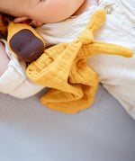 Käthe Kruse ocre yellow small Waldorf Imp doll baby comforter placed next to a baby.