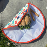 A close up view of the Keep Leaf food wrap in robot design on a grey blanket with a sandwich  packed inside