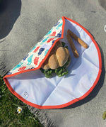 A close up view of the Keep Leaf food wrap in robot design on a grey blanket with a sandwich  packed inside