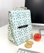 Keep Leaf insulated lunchbag in geo design on a desk next to an apple and crackers. 