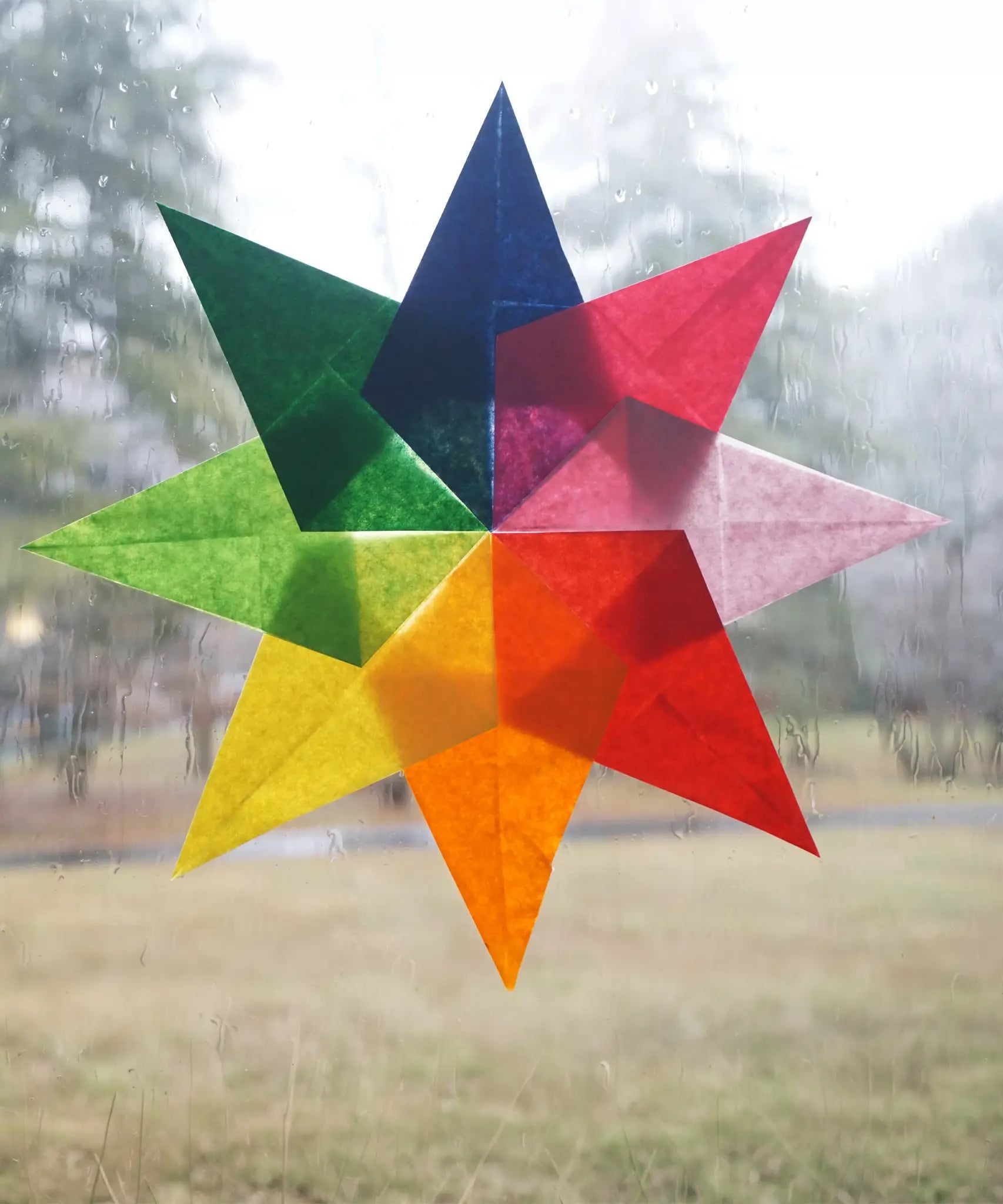 8 point star in rainbow colours made from kite wax paper stuck on a window