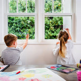 Two children drawing with the Kitpas eco-friendly coloured crayons on a window