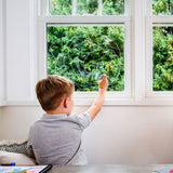 2 children crouched down drawing a town scene on a large piece of paper
