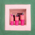 Klean Kanteen 16oz, 26 oz and 36oz rise insulated stainless steel bottle and tumblers standing in front of a window surrounded by white and green wall showing the pink colour way and handle detail on the tumblers
