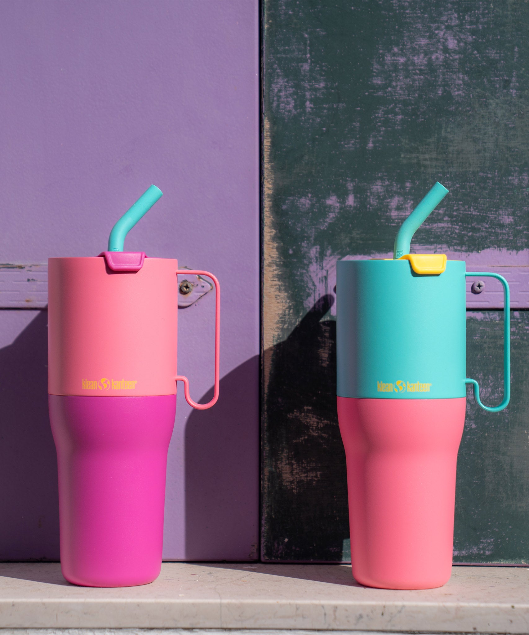 A Klean Kanteen 36oz klean kanteen stainless steel rise insulated tumbler standing on a stone surface next to a 36oz turquoise rise tumbler. 