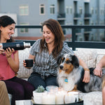 3 people and a dog sat on an outdoor sofa