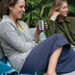 Woman sat down holding a Klean Kanteen plastic-free steel cup in front of a green background