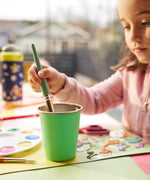A child using a Klean Kanteen Steel Kid Cup to clean a paint brush. 