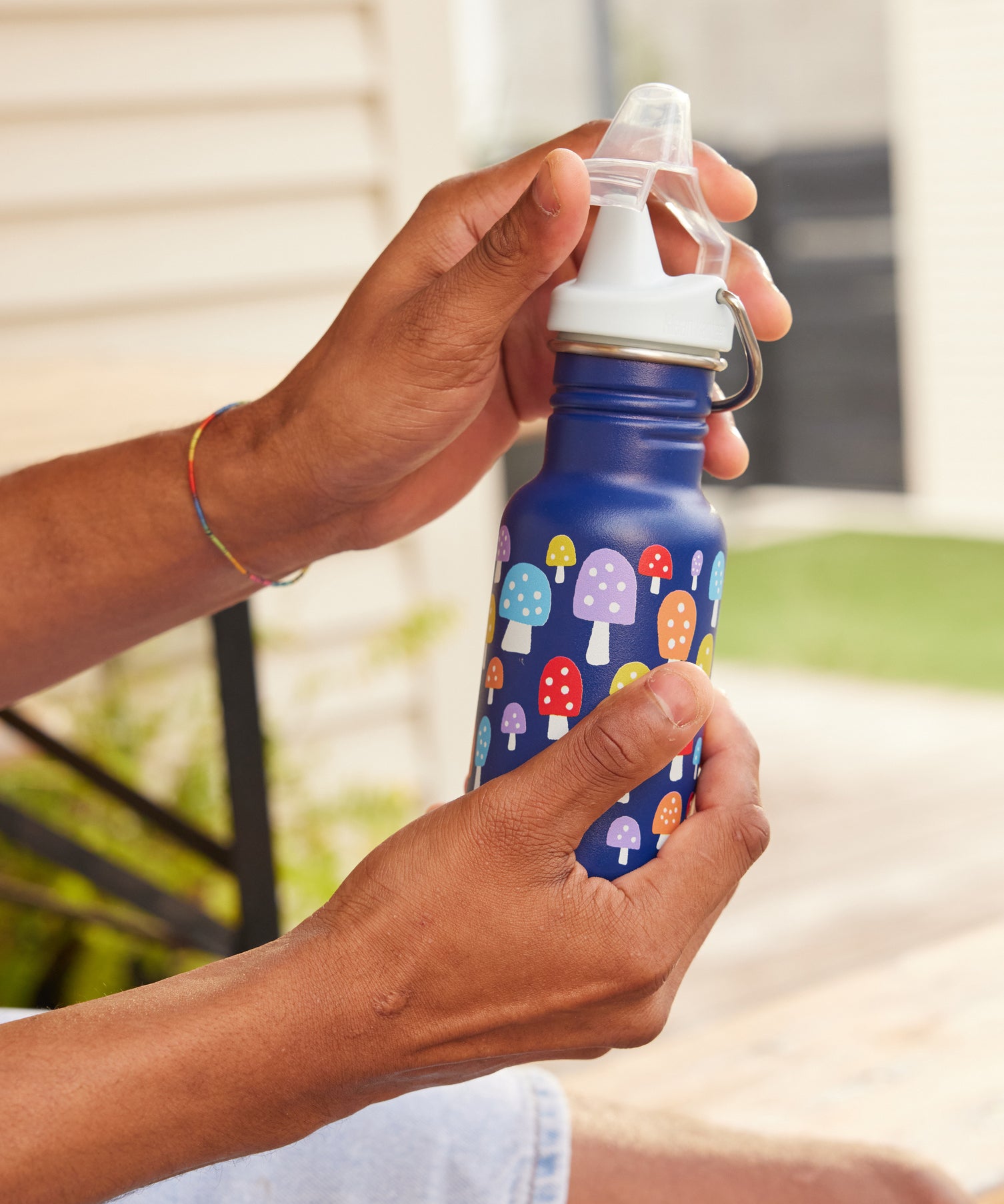 A close up of a mushroom print Kid Kanteen 12oz Narrow Sippy Bottle in an adult's hand. 