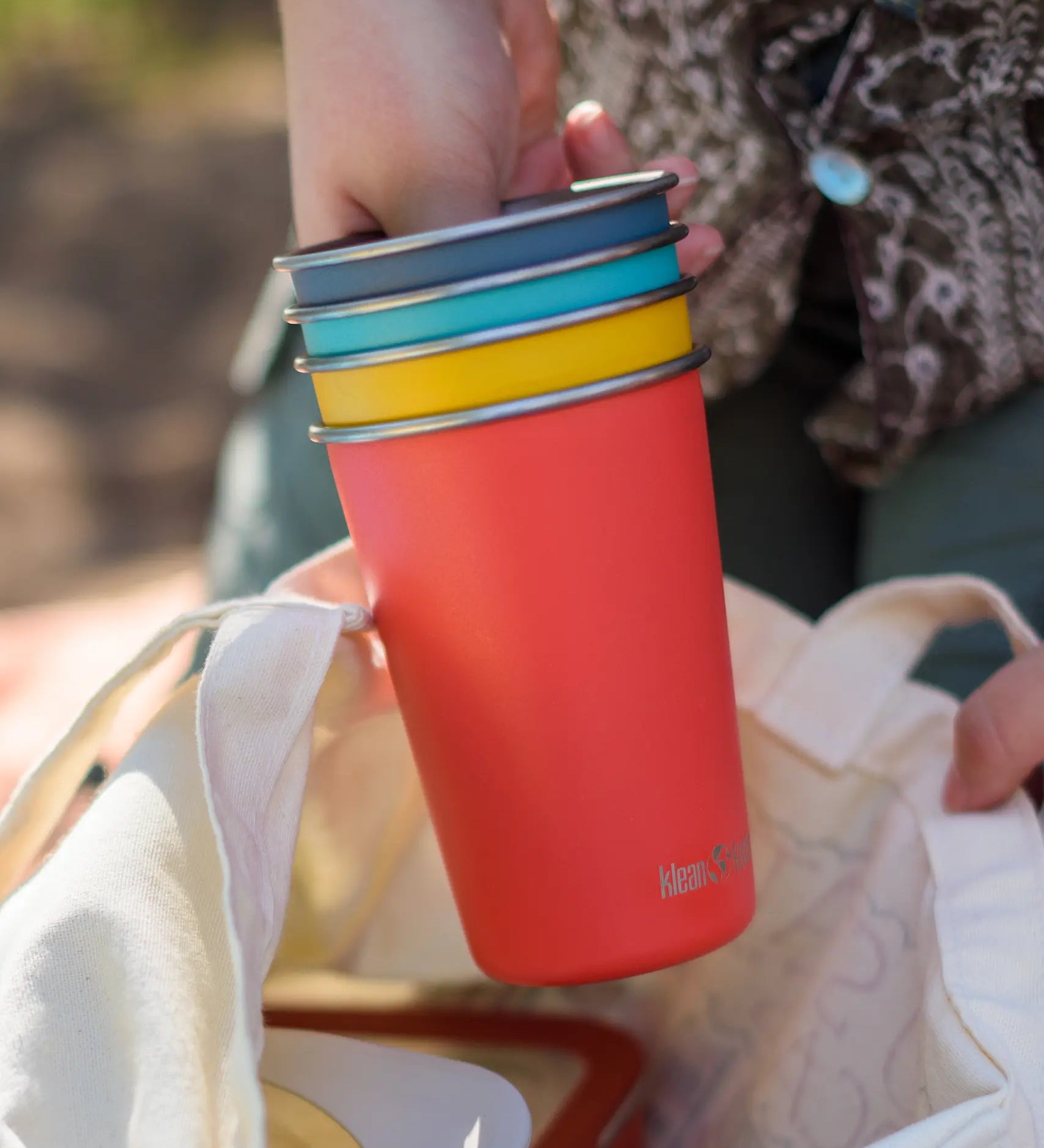 Klean Kanteen stainless steel 16oz pint cups in a 4 Pack in evening sky colours stacked together in a person's hands.