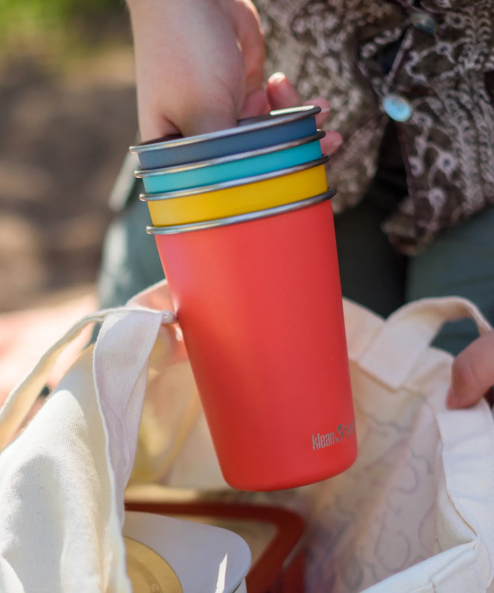 Klean Kanteen stainless steel 16oz pint cups in a 4 Pack in evening sky colours stacked together in a person's hands.