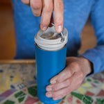 A close up of a person with a Klean Kanteen 16oz TKWide in corsair blue colour in their hand with taupe Cafe cap. 