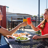 Two people with Klean Kanteen stainless steel 16oz pint cups in their hands making a cheering motion over a lunch table.