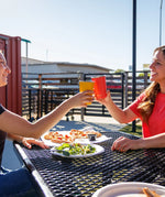 Two people with Klean Kanteen stainless steel 16oz pint cups in their hands making a cheering motion over a lunch table.