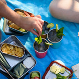Three Klean Kanteen stainless steel 16oz pint cups in evening sky colours filled with drinks and placed on a blue blanket.
