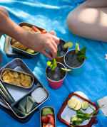 Three Klean Kanteen stainless steel 16oz pint cups in evening sky colours filled with drinks and placed on a blue blanket.