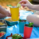 Yellow Klean Kanteen stainless steel 16oz steel pint cup filled with a drink in a person's hands with another person placing a lime on the side of the cup.