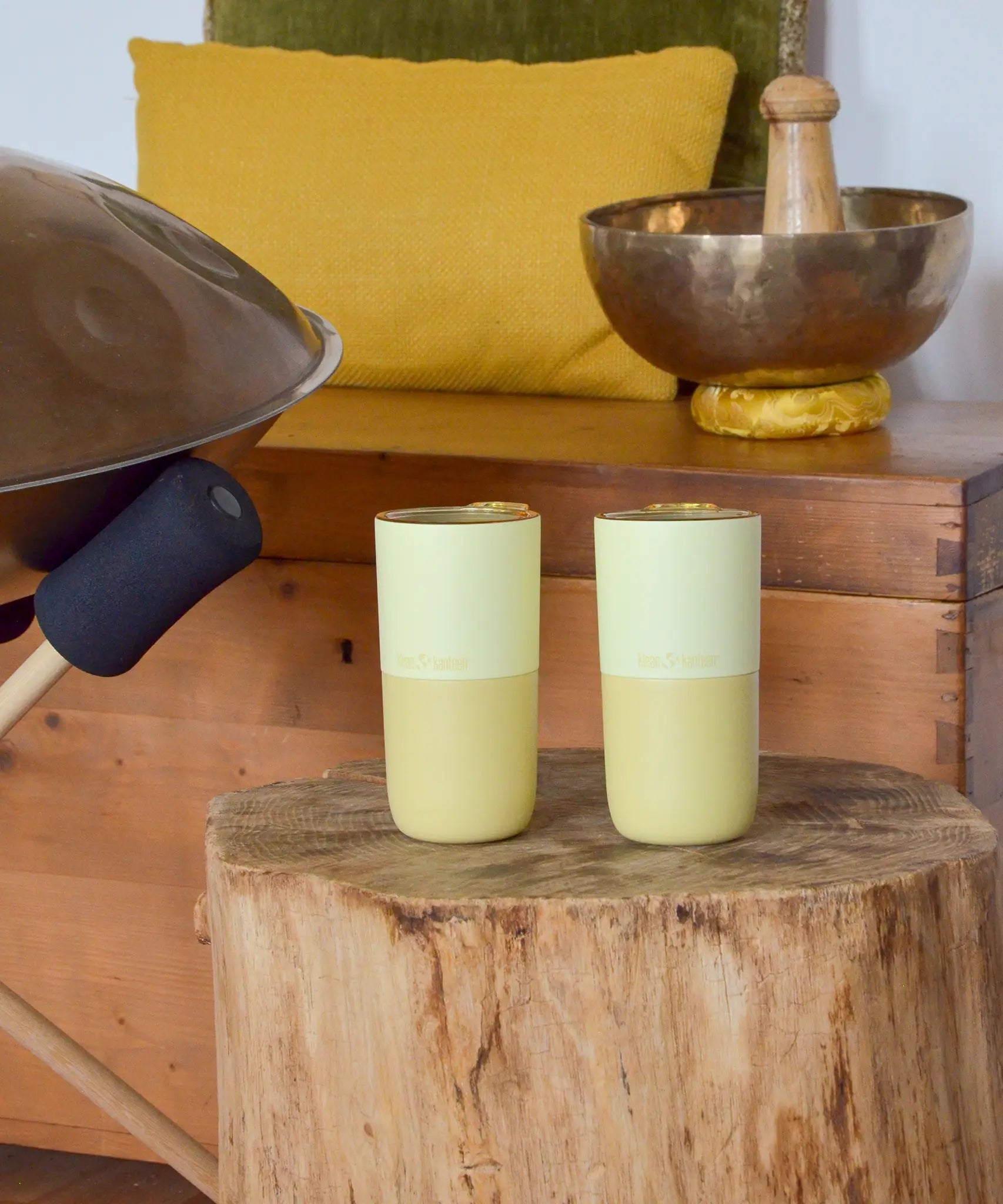 Pair of Klean Kanteen wax yellow 16oz stainless steel rise tumblers standing on a wooden table