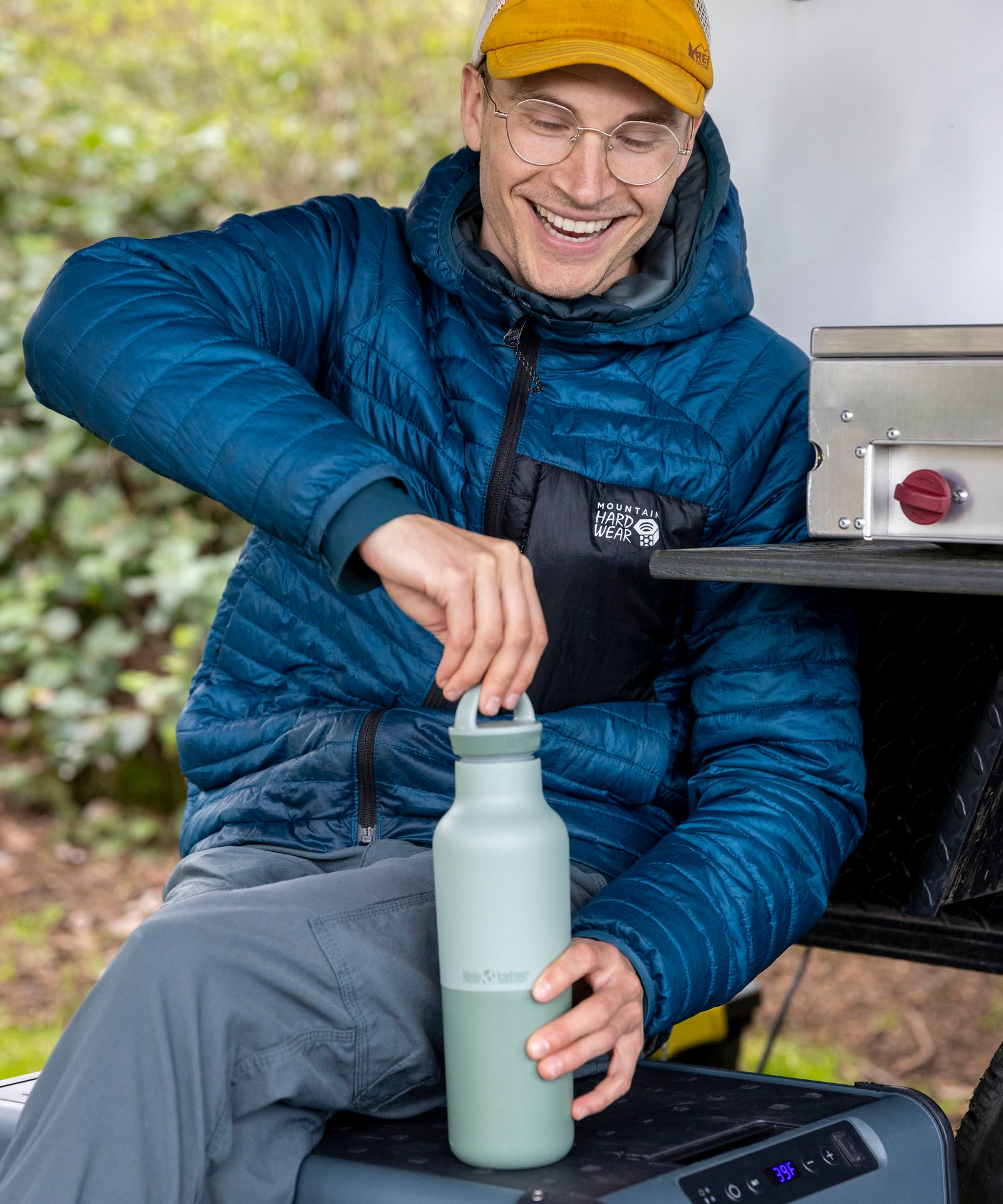 A man sitting outside and holding the iceberg 20oz rise Klean Kanteen water bottle and closing the matching loop cap on the bottle