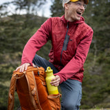 A man reaching out for a acacia 20oz Klean Kanteen rise Reusable Stainless Steel Water Bottle from a holder on a backpack 
