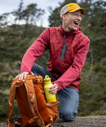 A man reaching out for a acacia 20oz Klean Kanteen rise Reusable Stainless Steel Water Bottle from a holder on a backpack 