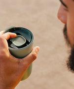 Man holding a Klean Kanteen 26oz sea spray green tumbler with a large 90mm rise slide lid on top