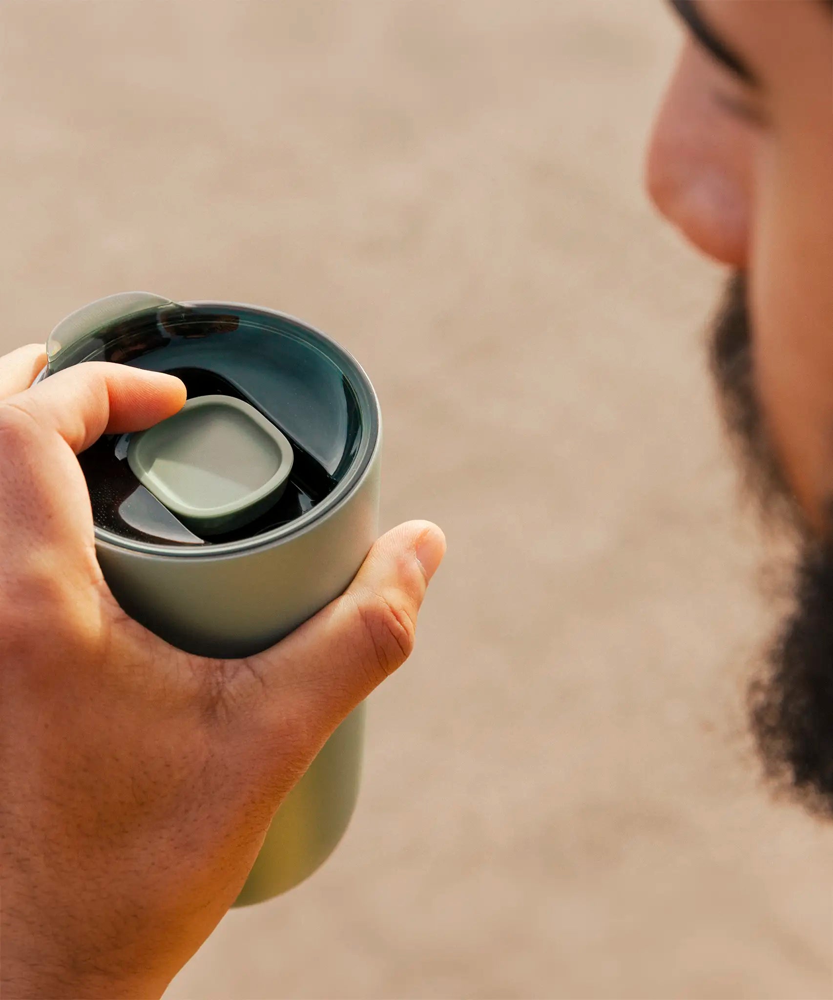 Man holding a Klean Kanteen 26oz sea spray green tumbler with a large 90mm rise slide lid on top