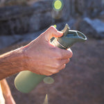 A close up of an adult holding a Sea Spray green coloured Klean Kanteen 27oz Classic Narrow Flip Seal Sports Cap Reusable Stainless Steel Water Bottle. They are opening the spout on the flip lid. 