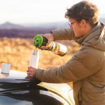 Close up of a man pouring liquid into a Klean kanteen 16oz tkpro stainless steel flask on the bonnet of a car