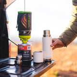 Close up of a Klean kanteen reusable tkpro flask on a car tailgate next to some camping equipment
