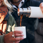 Close up of a man and woman pouring some liquid into the cup of a Klean kanteen 500ml tkpro insulated flask