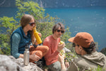 Three hikers enjoying a rest with an amazing view of the sea, drinking from their Klean Kanteens with flip seal sports caps.