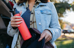 Close up of a woman putting a Klean Kanteen single wall steel bottle with a sports lid into a rucksack
