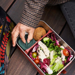 Person wearing a tweed jacket having lunch from the Klean Kanteen Rise Stainless Steel Big Meal Box with divider