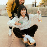 Adult sitting on a skateboard and holding a Klean Kanteen 8oz iceberg green lowball tumbler