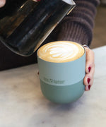 Adult hand holding a Klean Kanteen 8oz iceberg green lowball tumbler filled with coffee