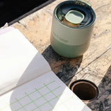 A iceberg green Klean Kanteen 8oz lowball tumbler with the slide lid on top standing on a wooden table
