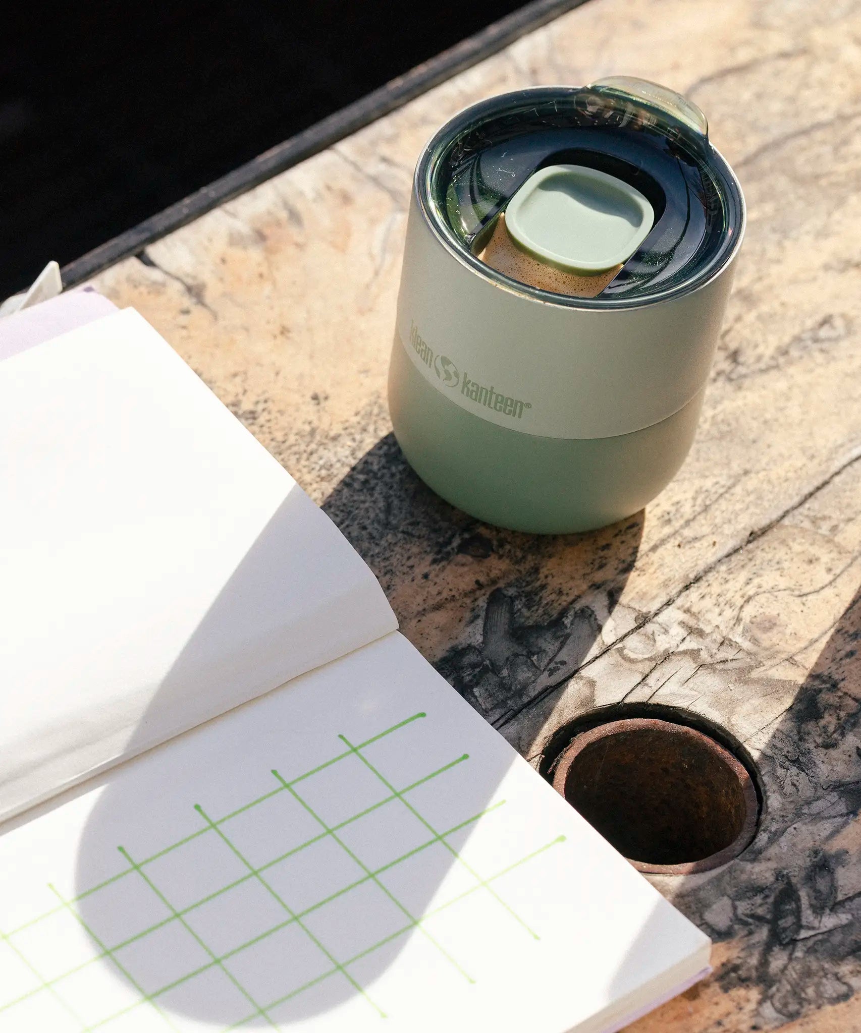 A iceberg green Klean Kanteen 8oz lowball tumbler with the slide lid on top standing on a wooden table